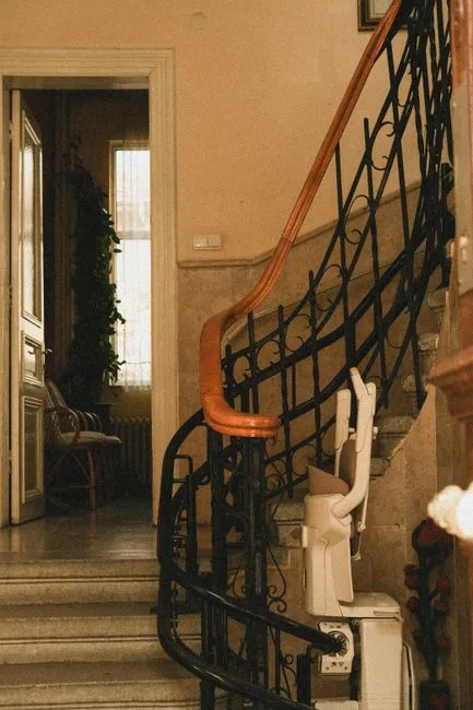 Monte-escalier à siège installé sur un escalier tournant à rampe en fer forgé